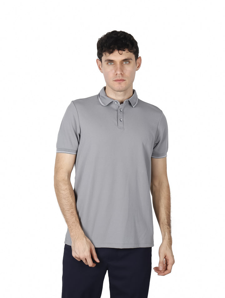 Hombre vistiendo una playera polo de color gris con detalles blancos en el cuello y mangas.