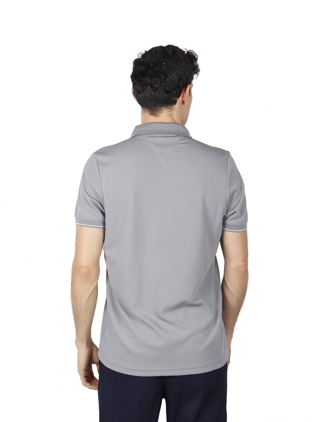 Hombre vistiendo una playera polo de color gris con detalles blancos en el cuello y mangas.