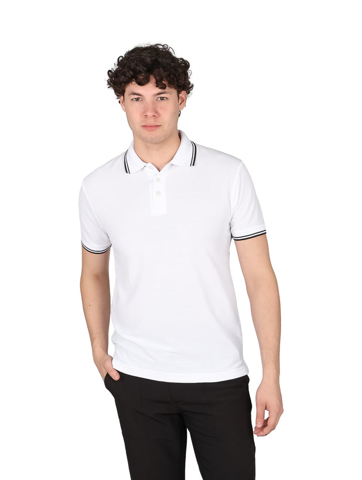 Hombre vistiendo una playera polo blanca con detalles negros en el cuello y los bordes de las mangas.
