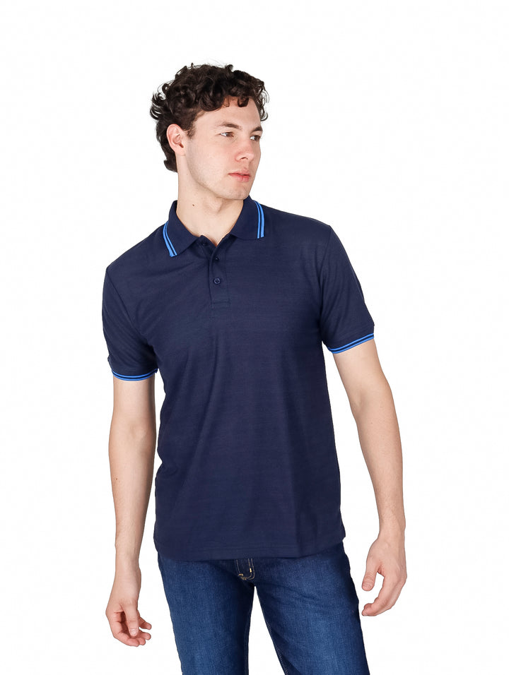 Hombre vistiendo una playera polo color azul marino con detalles en azul brillante en el cuello y mangas.