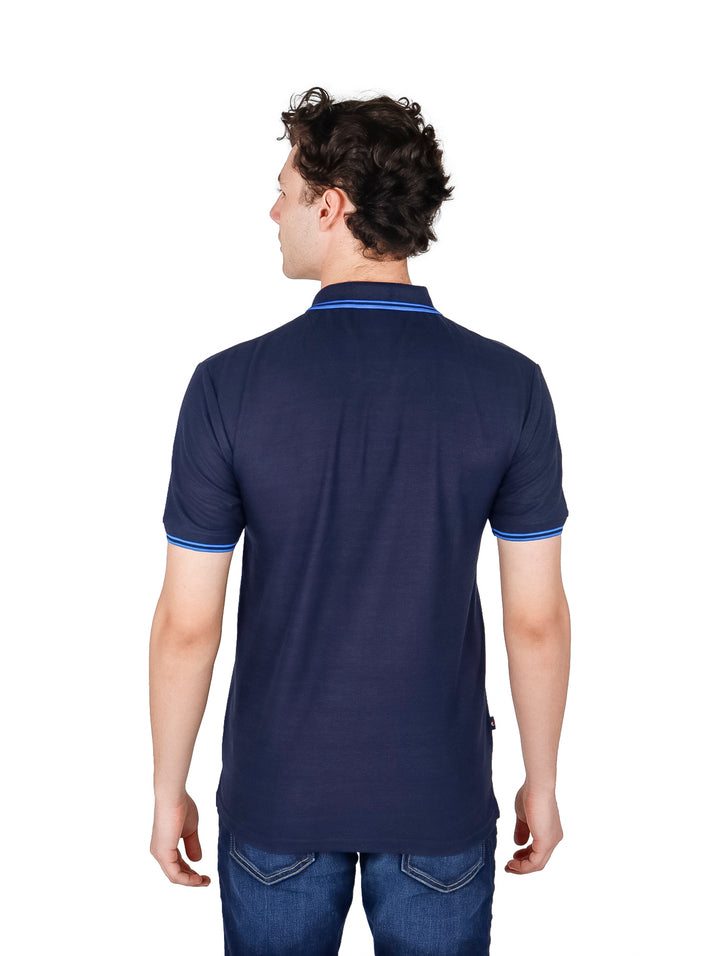 Hombre vistiendo una playera polo color azul marino con detalles en azul brillante en el cuello y mangas.