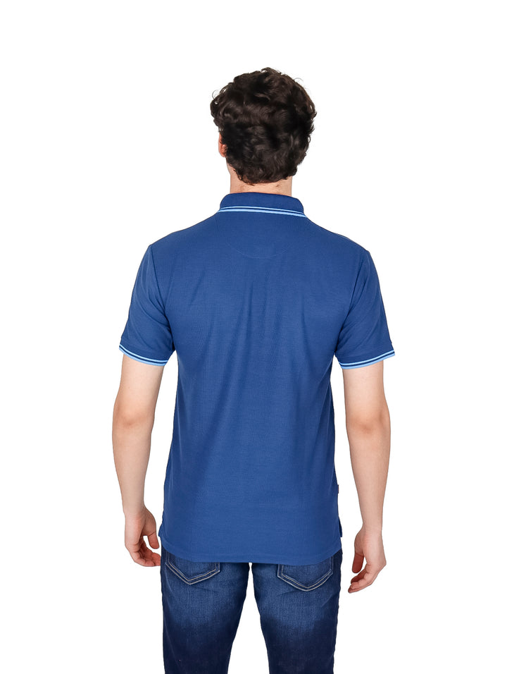 Hombre vistiendo una playera polo color azul índigo con detalles blancos en el cuello y mangas.