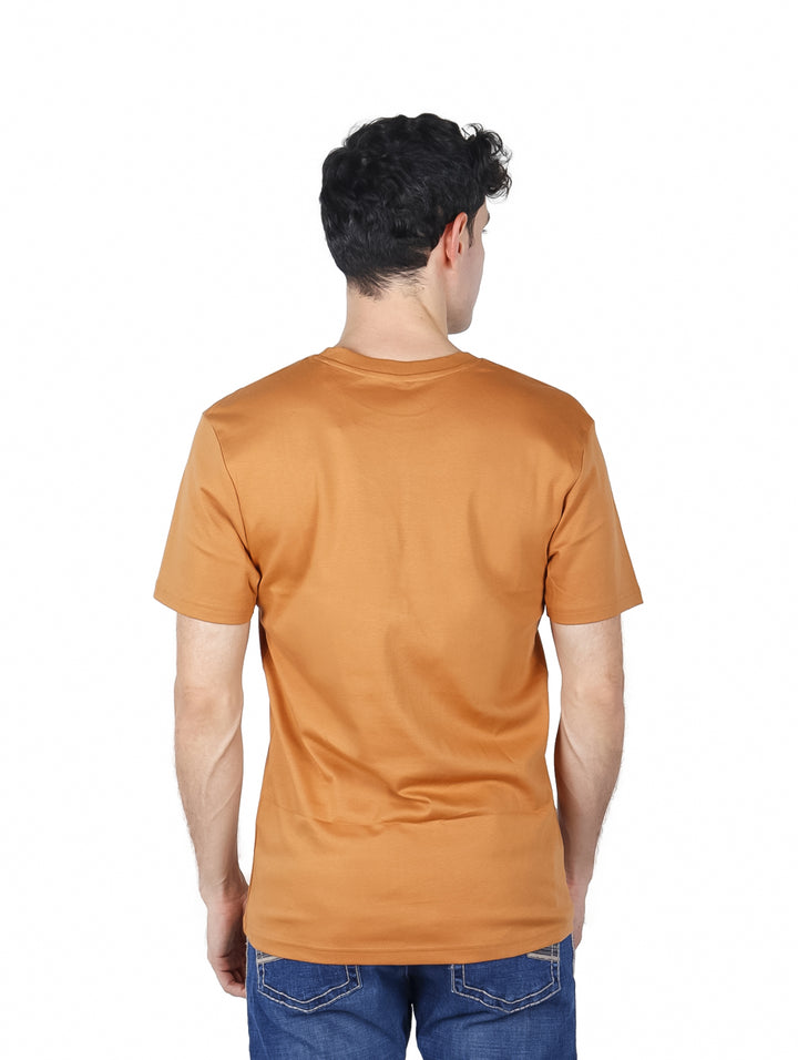 Hombre vistiendo una playera de manga corta color marrón con un pequeño logo blanco en el pecho.