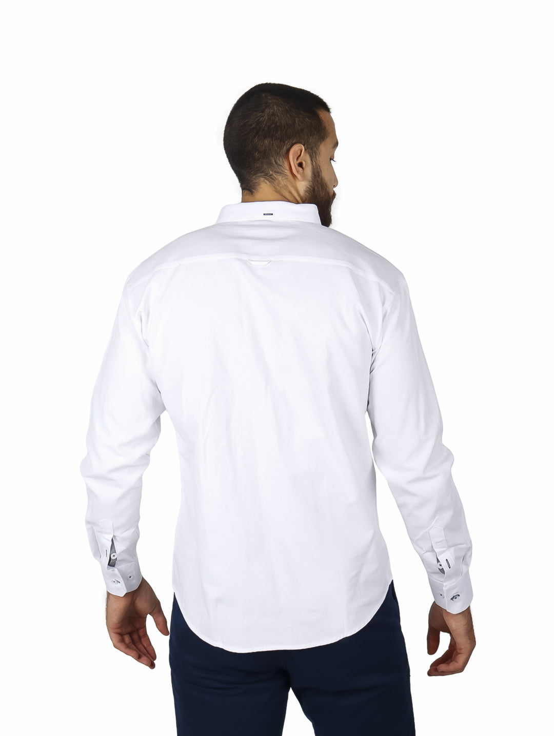 Hombre vistiendo camisa blanca de manga larga con detalle de rayas rojas y azules en el pecho.