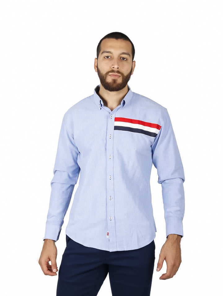 Camisa azul claro de manga larga con detalles de franjas rojas y azul marino en el pecho.