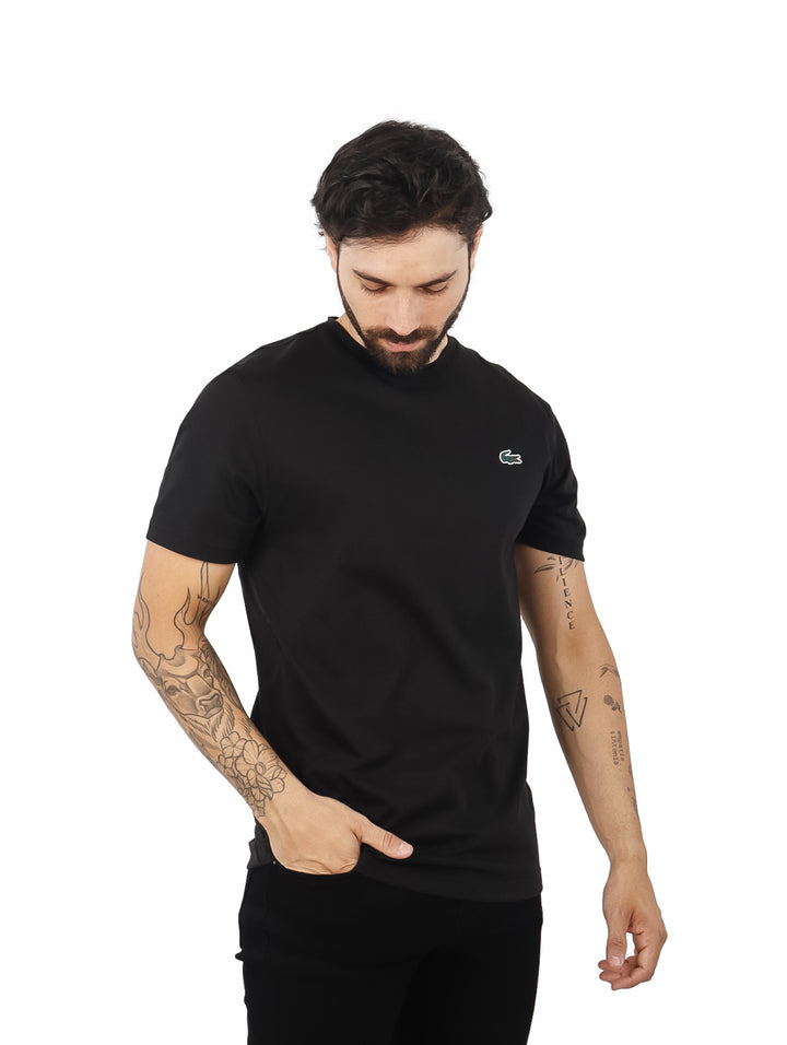 Hombre vistiendo una camiseta de manga corta color negro de la marca Lacoste.