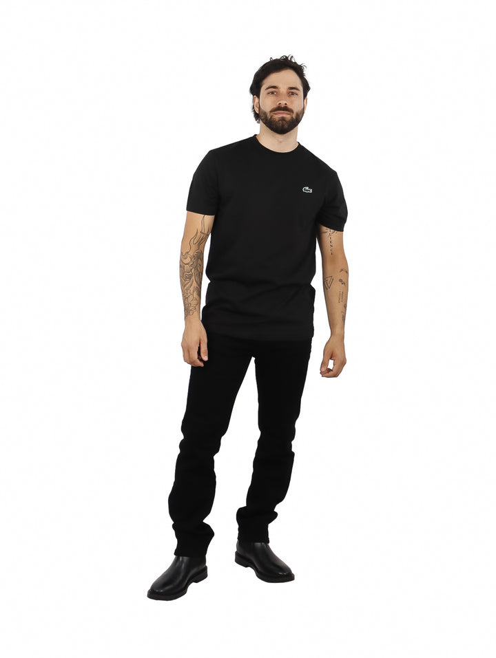 Hombre vistiendo una camiseta de manga corta color negro de la marca Lacoste.
