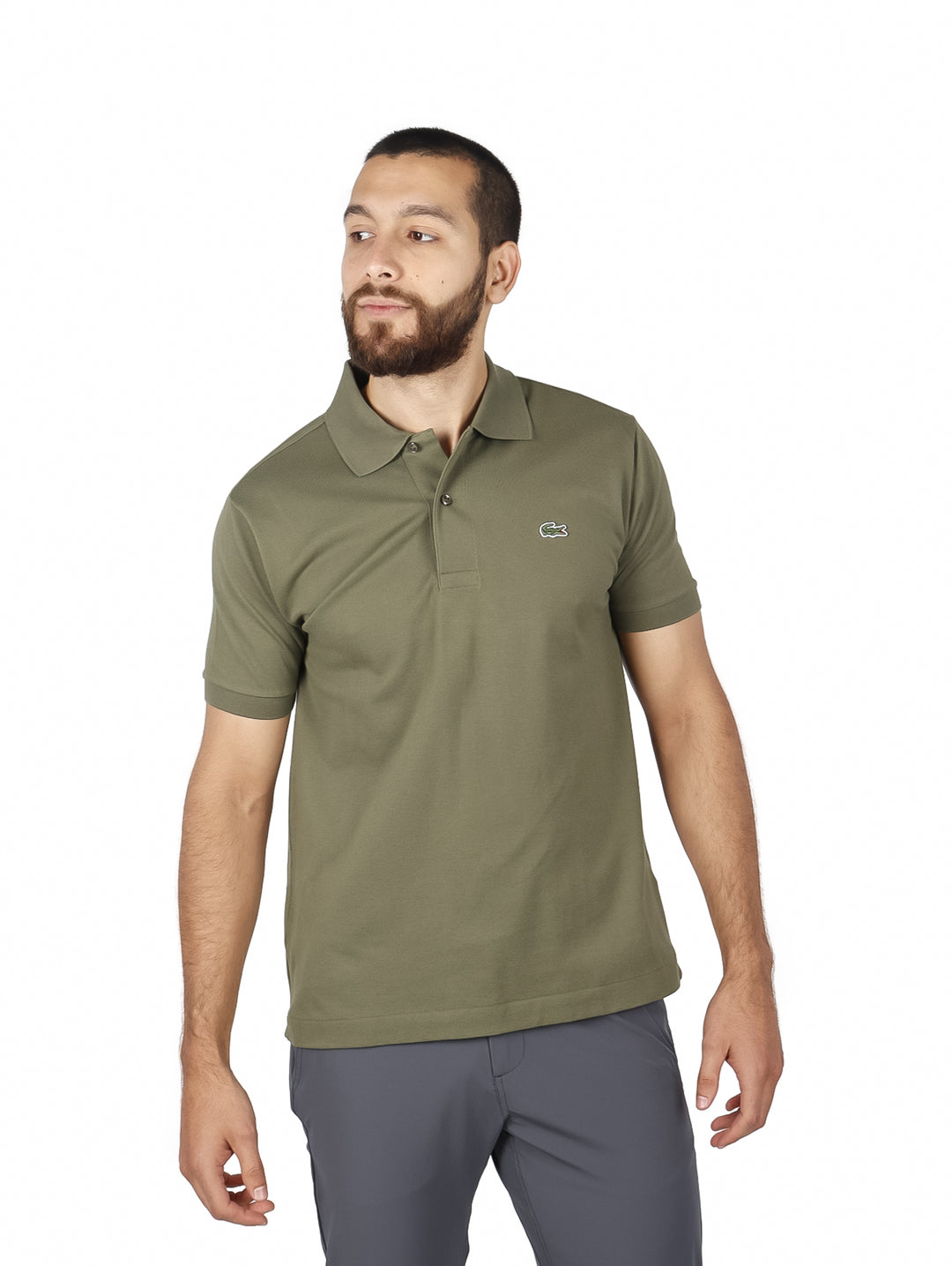 Hombre vistiendo una playera polo de color verde olivo de la marca Lacoste con cuello y manga corta.