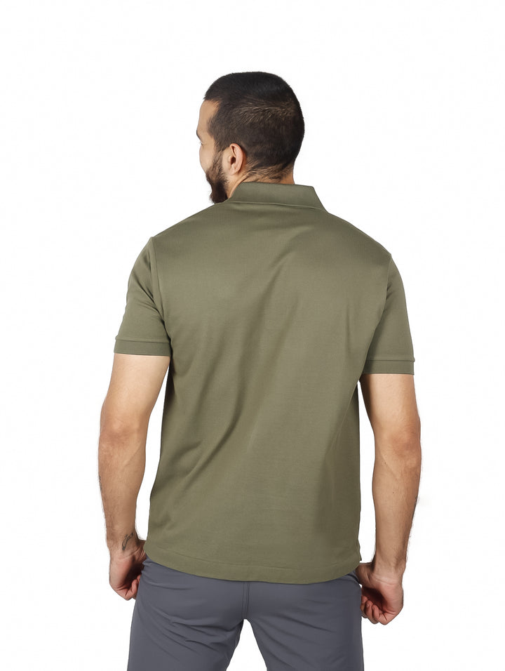 Hombre vistiendo una playera polo de color verde olivo de la marca Lacoste con cuello y manga corta.
