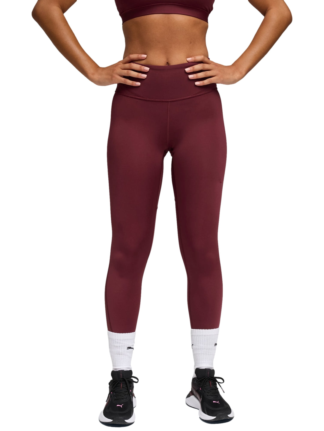 Mujer vistiendo leggings deportivos PUMA de color rojo vino, corte 7/8 y cintura alta.