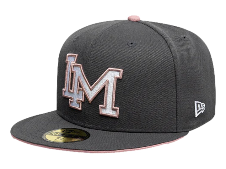 Gorra New Era color gris oscuro con visera plana y letras bordadas en blanco y rosa en el frente.