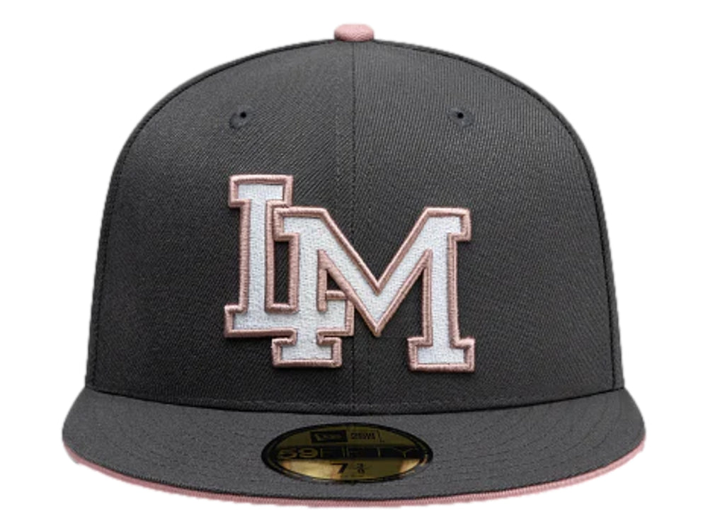 Gorra New Era color gris oscuro con visera plana y letras bordadas en blanco y rosa en el frente.