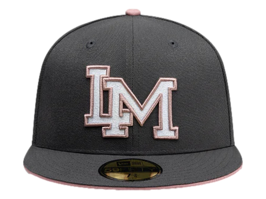 Gorra New Era color gris oscuro con visera plana y letras bordadas en blanco y rosa en el frente.