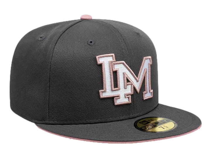 Gorra New Era color gris oscuro con visera plana y letras bordadas en blanco y rosa en el frente.