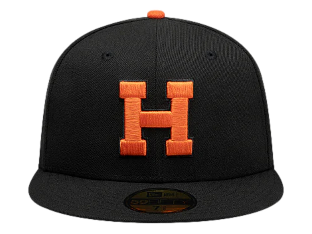 Gorra New Era color negro con logotipo bordado en naranja y visera plana.