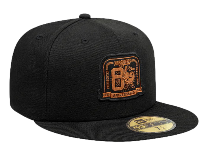 Gorra New Era negra con visera plana y logotipo bordado en color dorado en el frente.