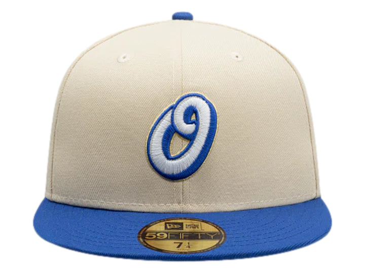 Gorra New Era color beige con visera azul y logotipo bordado en el frente.