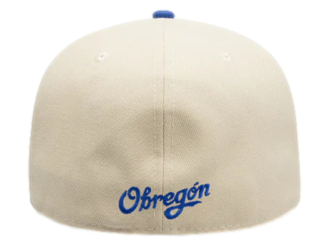 Gorra New Era color beige con visera azul y logotipo bordado en el frente.