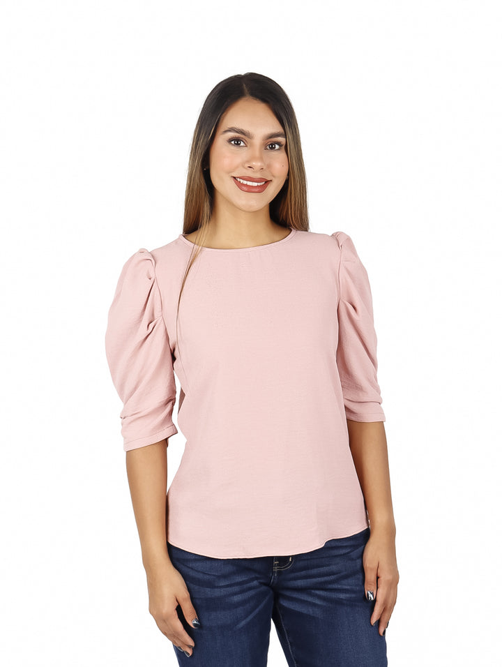 Mujer vistiendo una blusa rosa de manga 3/4 con cuello redondo y pantalones vaqueros azules.
