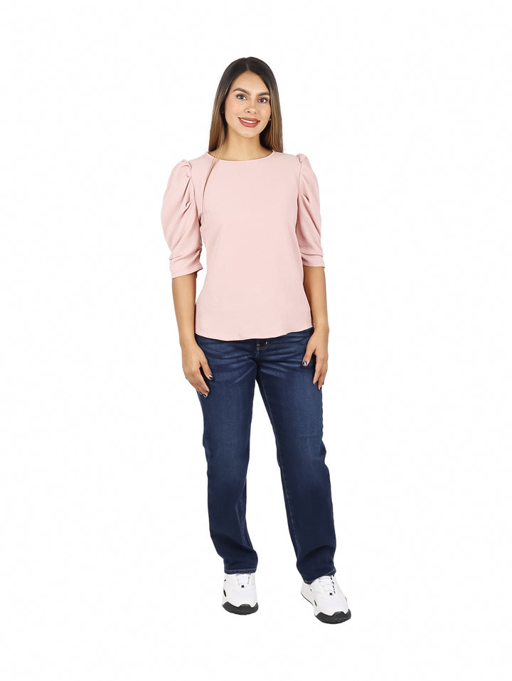 Mujer vistiendo una blusa rosa de manga 3/4 con cuello redondo y pantalones vaqueros azules.