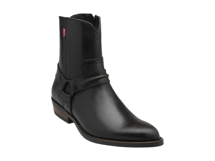 Bota negra de material sintético con correa y hebilla, suela marrón y etiqueta roja de marca.