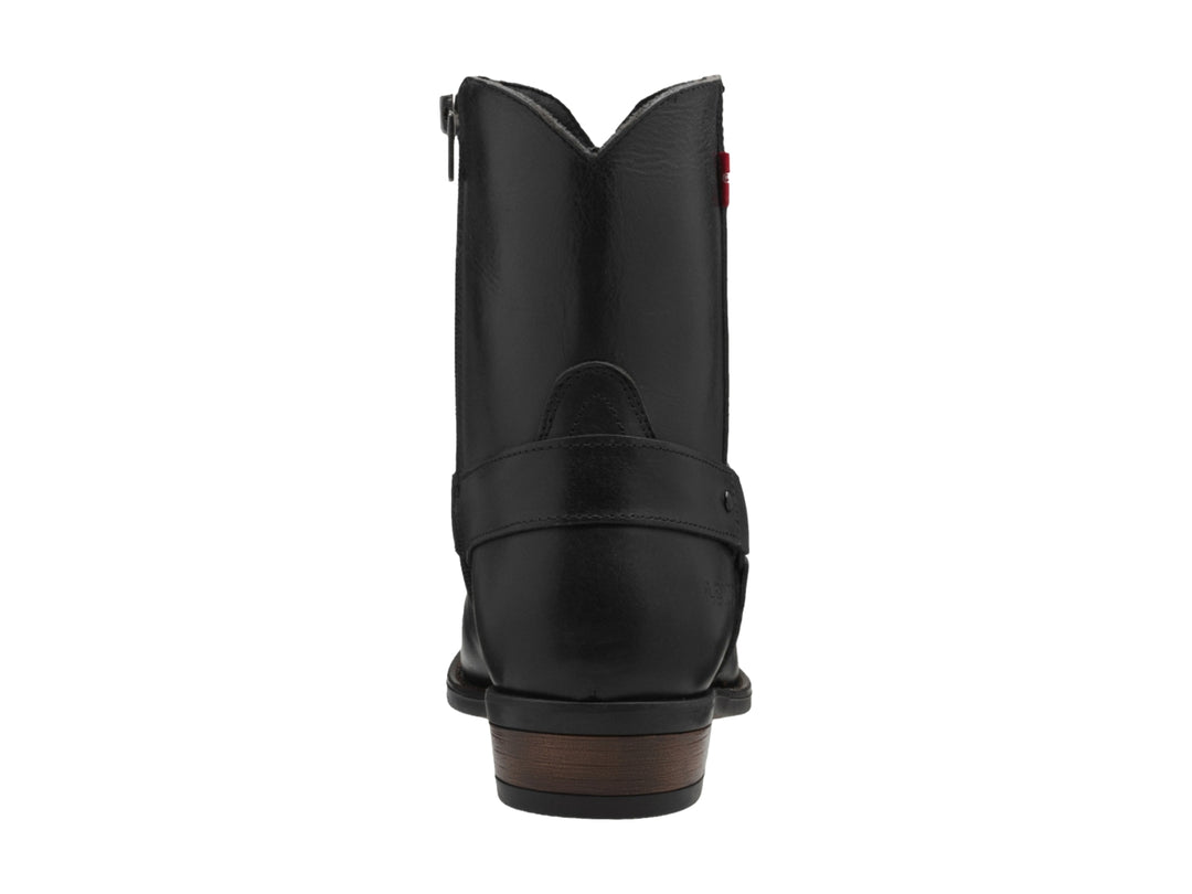 Bota negra de material sintético con correa y hebilla, suela marrón y etiqueta roja de marca.