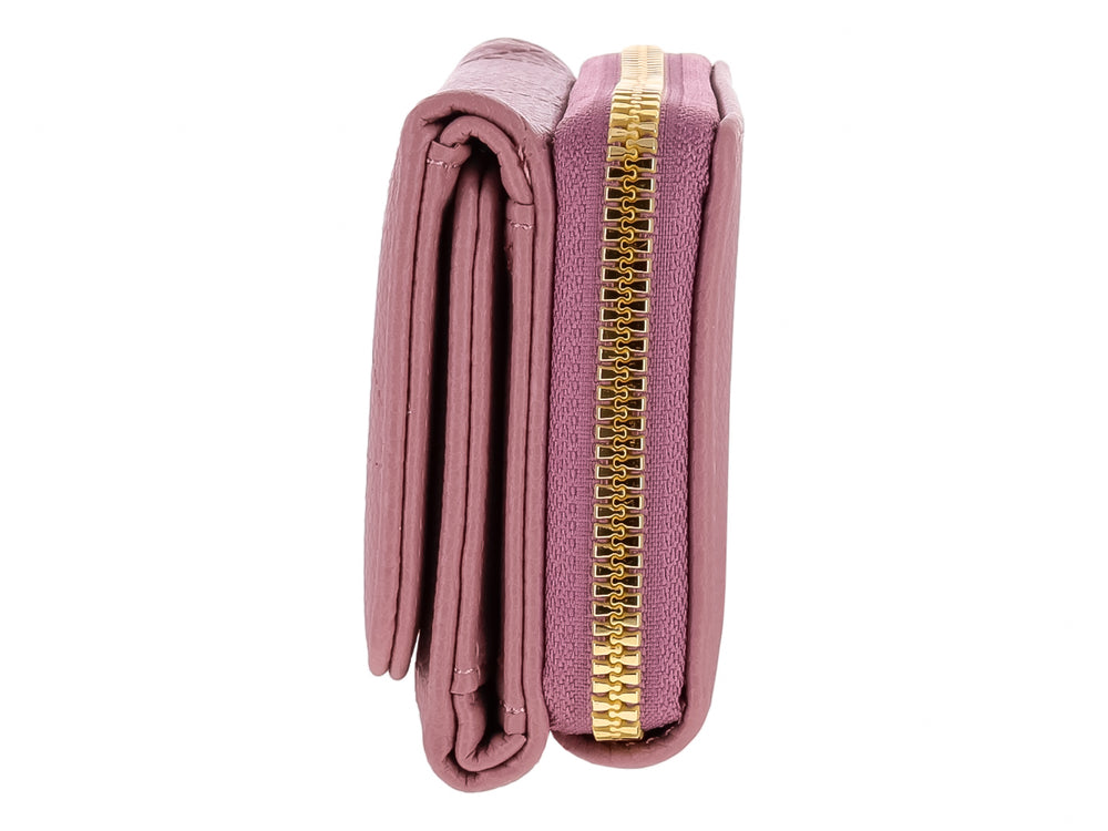 Monedero color morado con textura rugosa y un adorno triangular dorado en el cierre frontal.