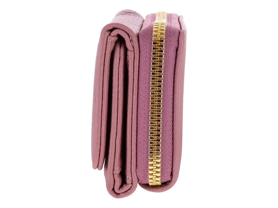Monedero color morado con textura rugosa y un adorno triangular dorado en el cierre frontal.