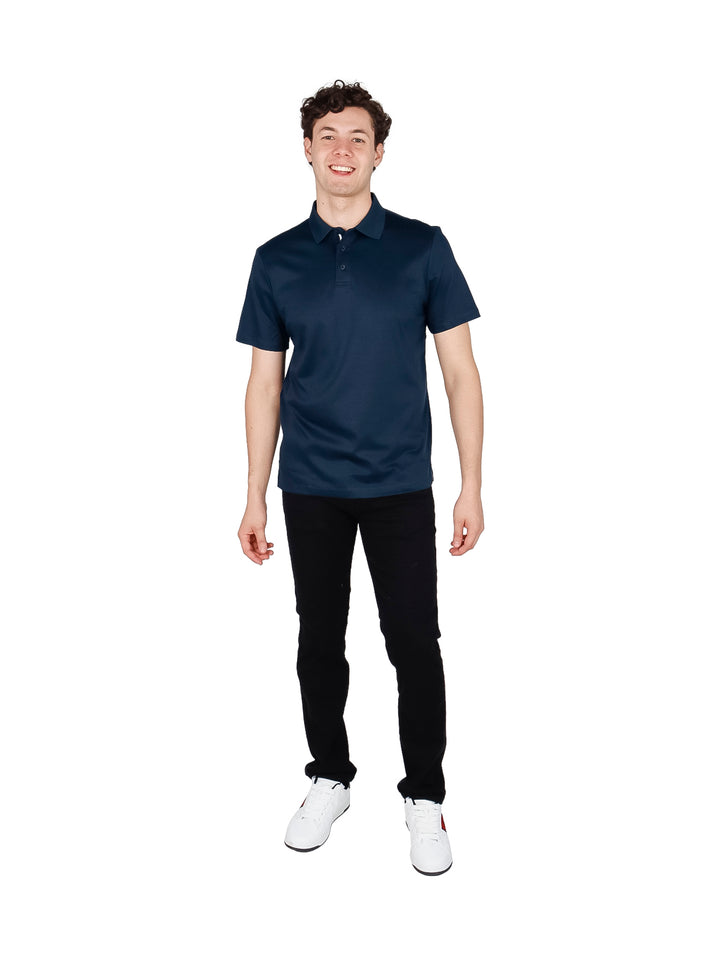 Hombre vistiendo una camiseta polo de color azul oscuro con cuello y manga corta.