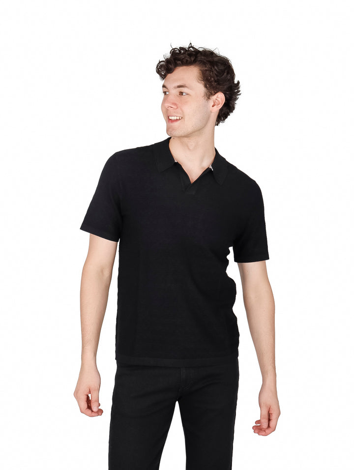 Hombre vistiendo una camiseta polo de manga corta color negro.