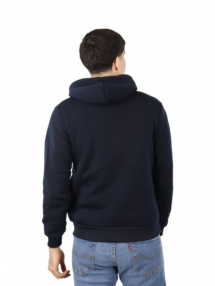 Hombre vistiendo una sudadera con capucha color marino con bolsillo frontal.