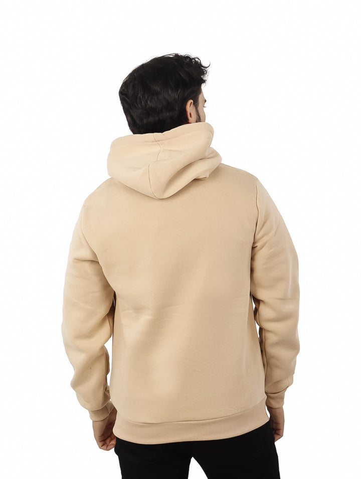 Hombre vistiendo sudadera con capucha color beige, con bolsillo frontal y ajuste casual.