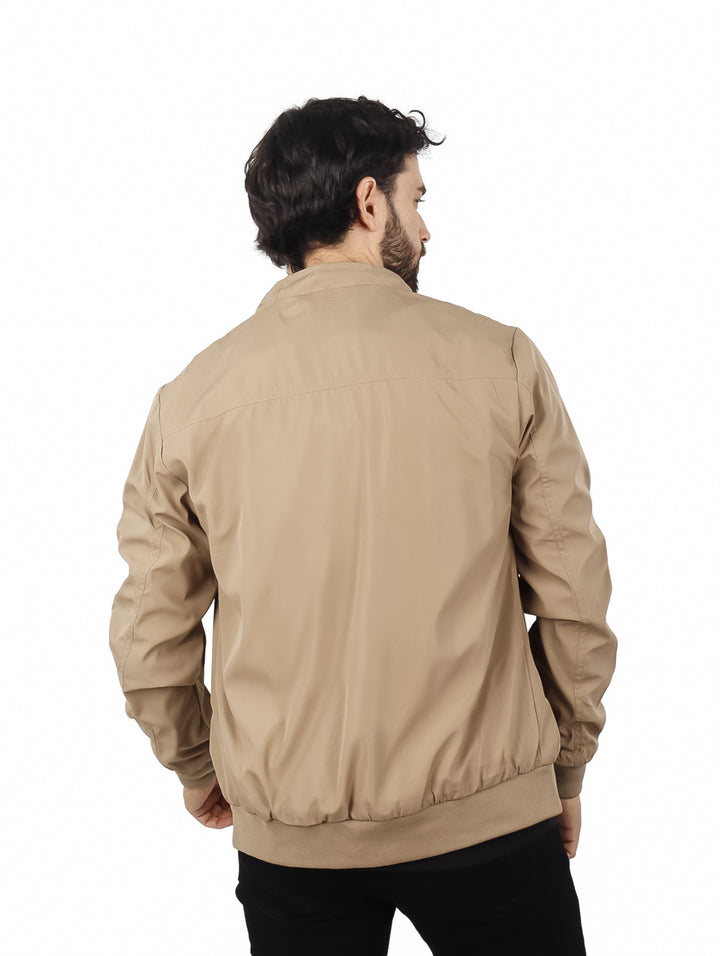 Hombre usando una chamarra tipo bomber de color beige con camiseta negra.