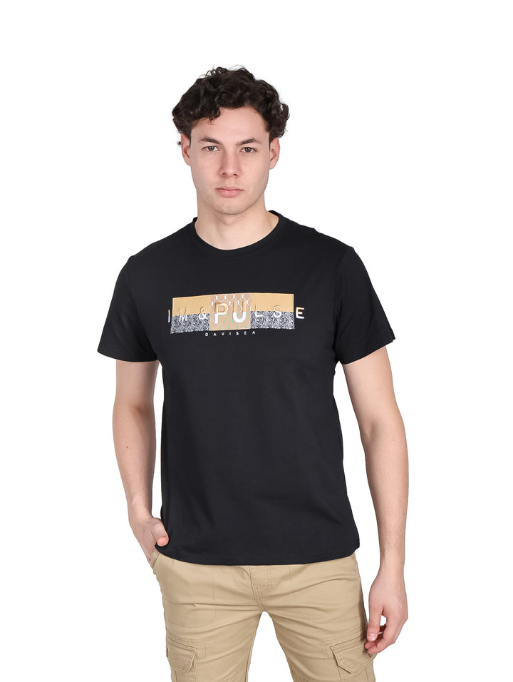 Hombre vistiendo una playera negra de manga corta con estampado frontal y pantalones color beige.
