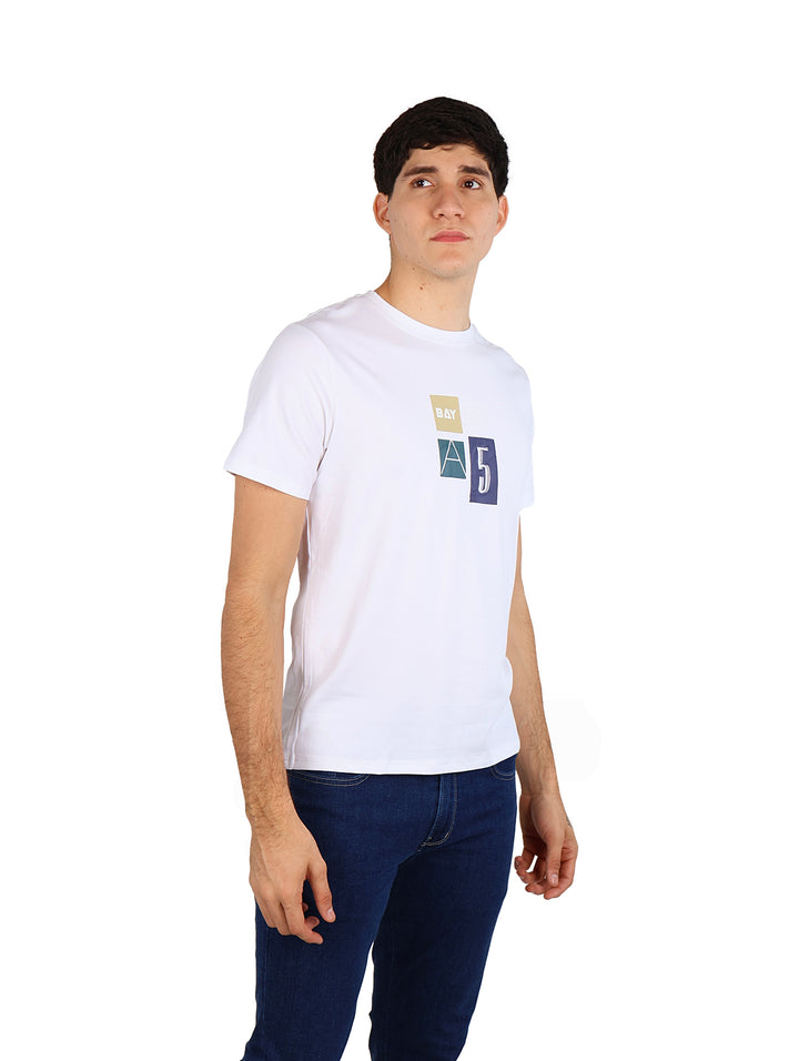 Hombre vistiendo una playera blanca de manga corta con un pequeño estampado gráfico en el pecho.