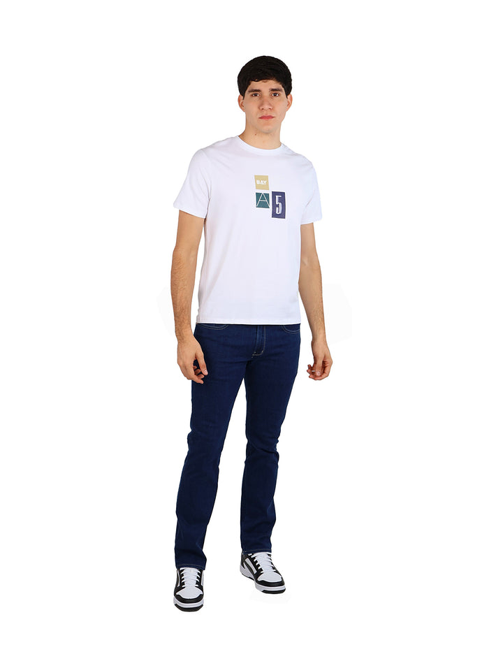 Hombre vistiendo una playera blanca de manga corta con un pequeño estampado gráfico en el pecho.