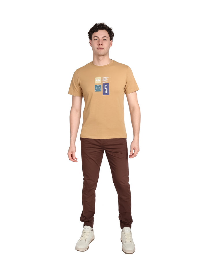 Hombre vistiendo playera de manga corta color café con estampado geométrico en el pecho.