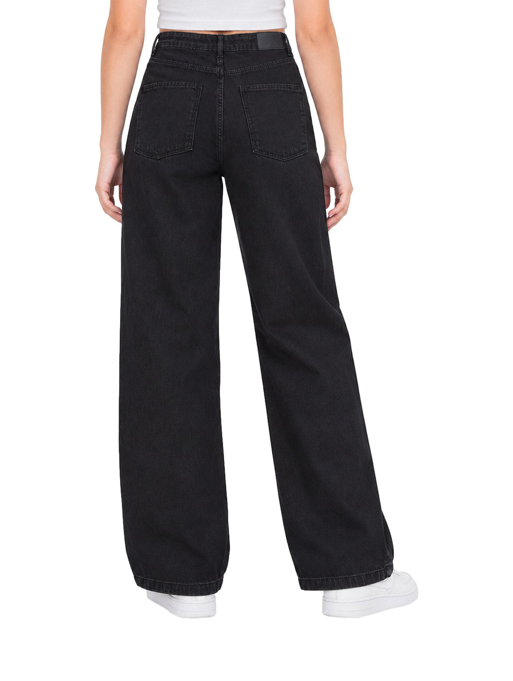 Mujer vistiendo pantalones Losan de denim negro, corte ancho y talle alto con tenis blancos.