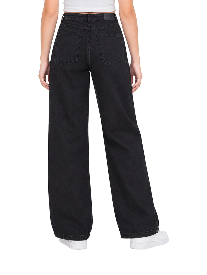 Mujer vistiendo pantalones Losan de denim negro, corte ancho y talle alto con tenis blancos.