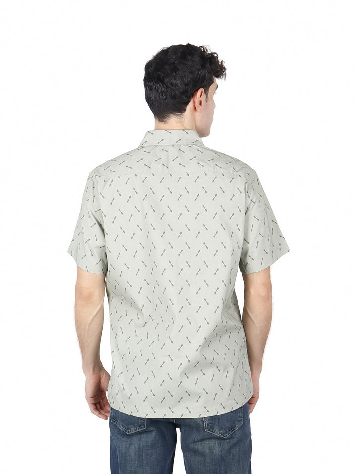 Hombre vistiendo una camisa de manga corta color oliva con un estampado pequeño y botones.