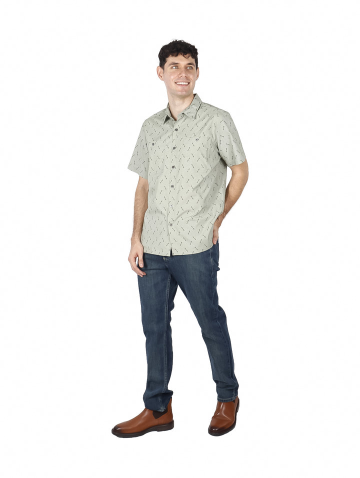 Hombre vistiendo una camisa de manga corta color oliva con un estampado pequeño y botones.