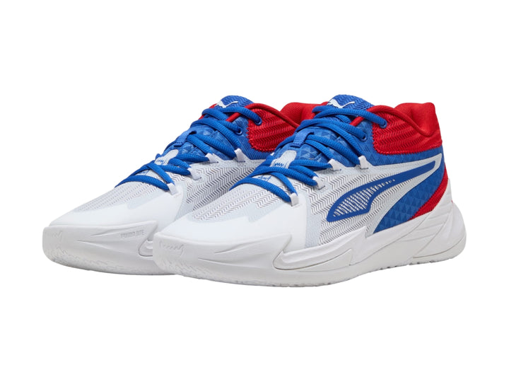 Tenis de baloncesto PUMA en colores blanco, rojo y azul con suela blanca y diseño moderno.