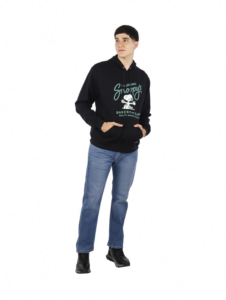 Hombre vistiendo sudadera con capucha color negro con estampado de Snoopy Bakery and Cafe en el pecho.