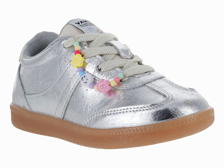 Tenis plateados metálicos con suela café y adornos de flores coloridas en las agujetas.