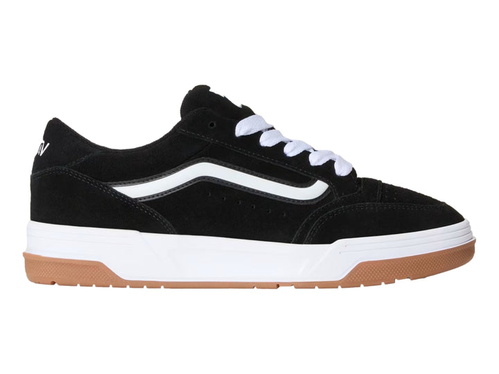 Tenis Vans color negro con franja blanca, suela blanca y base de goma color marrón.