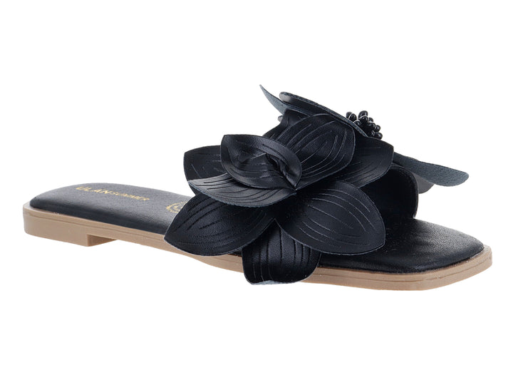 Sandalia plana color negro con un adorno de flor grande en la correa superior.