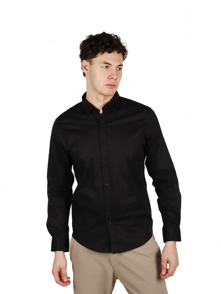 Hombre vistiendo una camisa lisa de color negro con manga larga y cuello, estilo elegante.