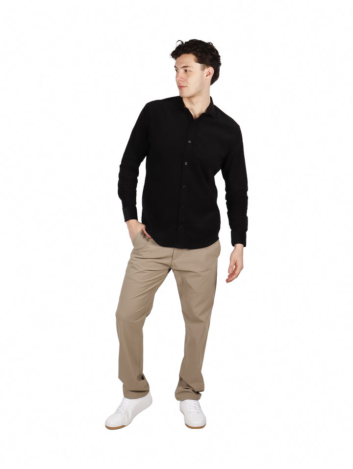 Hombre vistiendo una camisa lisa de color negro con manga larga y cuello, estilo elegante.