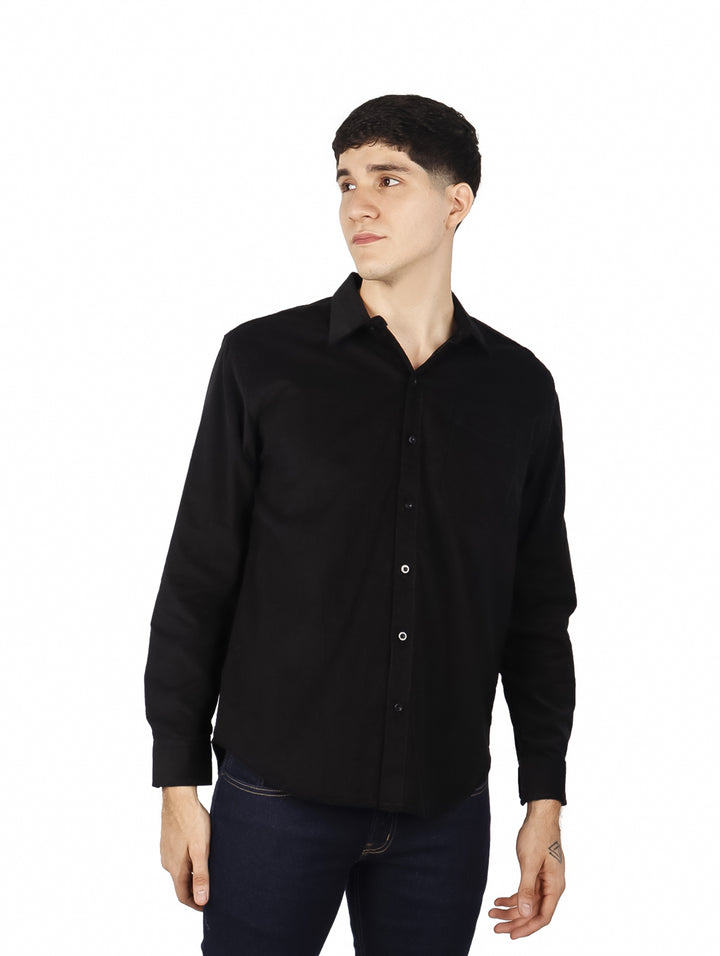 Hombre vistiendo una camisa de pana color negro de manga larga con botones frontales.
