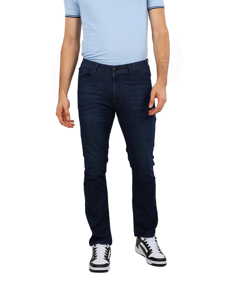 Hombre vistiendo pantalones jeans rectos de color azul oscuro, camiseta azul claro y tenis blancos con negro.